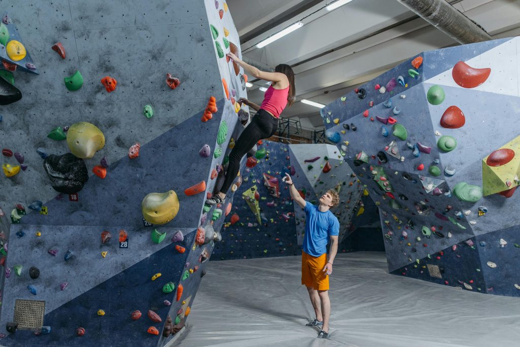 Two athletes engaged in indoor rock climbing on a colorful climbing wall.
